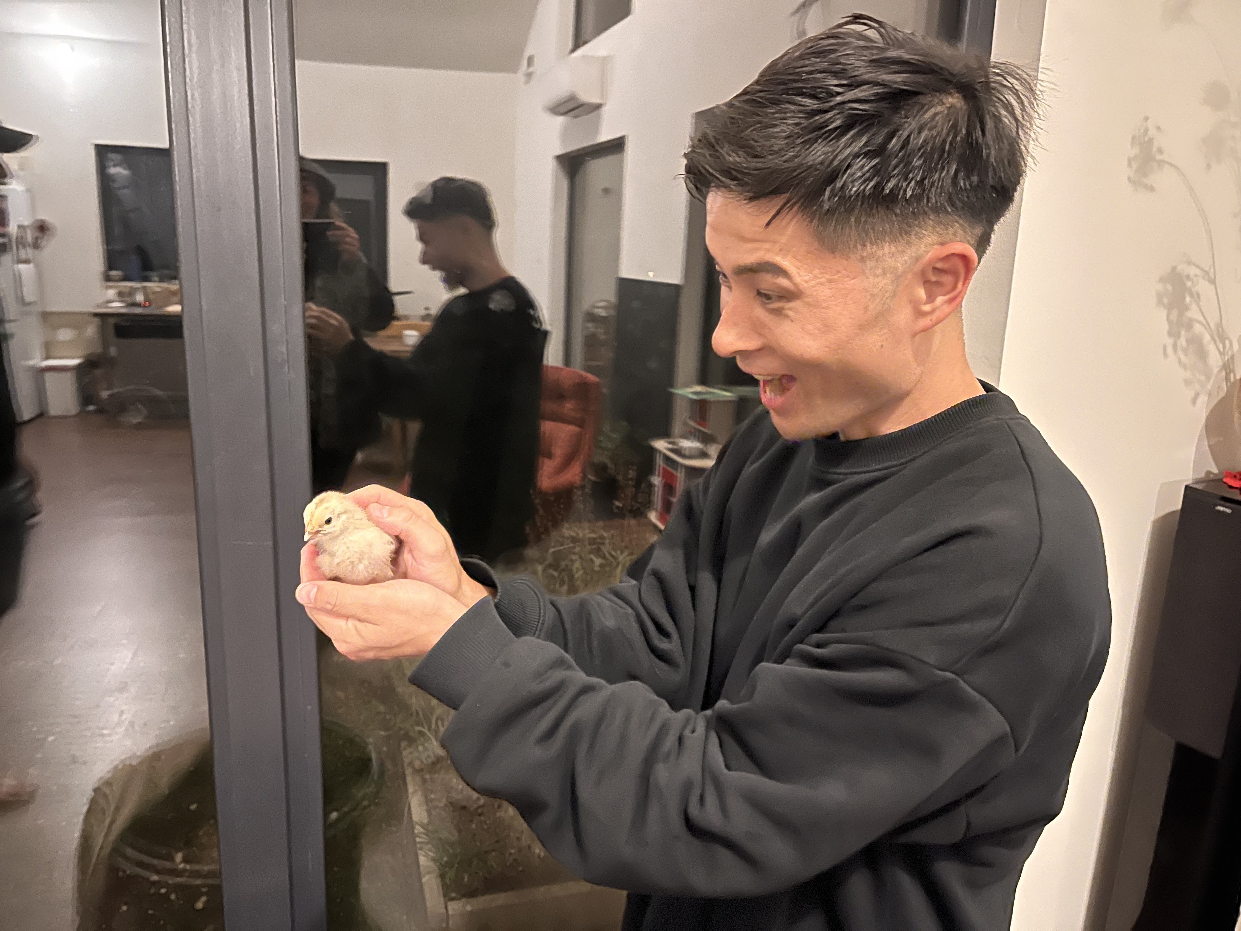 Aki smiling while holding a new born chick in his hands